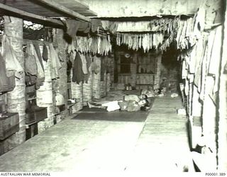 NEW IRELAND, 1945-10. INTERIOR OF A JAPANESE LIVING HUT WITH SOME RESIDENTS RESTING. (RNZAF OFFICIAL PHOTOGRAPH.)