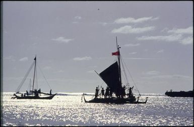 Silhouette of boat with triangle sail with people aboard