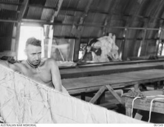 3 MILE, PORT MORESBY, NEW GUINEA. 1943-12-14. NX73458 PRIVATE J. PALMER OF THE 1ST AUSTRALIAN PARACHUTE REFOLDING PLATOON, AUSTRALIAN ARMY ORDNANCE CORPS, REFOLDING A PARACHUTE AFTER AN INSPECTION