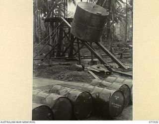 MILNE BAY, PAPUA, NEW GUINEA. 1944-03-31. MEMBERS OF THE 1ST FIELD SQUADRON, ROYAL AUSTRALIAN ENGINEERS, SLIDE A 6,000 GALLON DIESEL OIL TANK INTO POSITION ON A STAND, USING A POWER DRIVEN WINCH ..