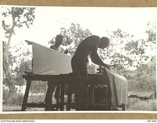 17 MILE, PORT MORESBY AREA, NEW GUINEA. 1943-12-13. PERSONNEL OF THE TENT REPAIR SECTION, RETURNED STORES SECTION, 10TH AUSTRALIAN ADVANCED ORDNANCE DEPOT IN THEIR WORKSHOP FITTING NEW COVERS TO ..