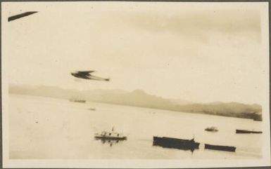 Charles Kingsford-Smith's Fokker FVIIB-3m monoplane, the Southern Cross flying above boats on ocean, Fiji, June 1928