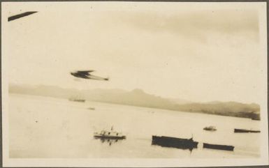 Charles Kingsford-Smith's Fokker FVIIB-3m monoplane, the Southern Cross flying above boats on ocean, Fiji, June 1928