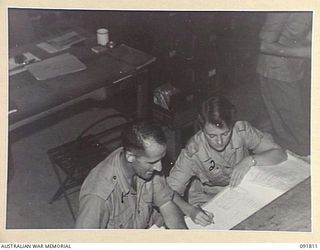 LAE, NEW GUINEA. 1945-05-15. PRIVATE J. MCARTHUR (2), RECEIVES INSTRUCTIONS FROM TROOPER F.J. HENDERSON (1), AT A BRANCH, HEADQUARTERS FIRST ARMY. A FEW DAYS AFTER THEIR ARRIVAL FROM AUSTRALIA ..