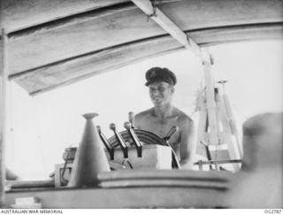 AITAPE, NORTH EAST NEW GUINEA. C. 1945. THE SKIPPER OF A RAAF AIR-SEA RESCUE LAUNCH, WARRANT OFFICER LESTER CRIBB OF EVANS HEAD, NSW, AT THE HELM OF HIS BOAT A MAN OF THE SEA