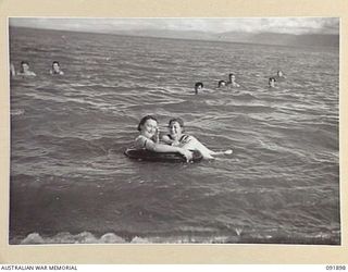 LAE, NEW GUINEA, 1945-05-18. SIGNALWOMAN D. TABE (1), AND SIGNALWOMAN E.G. MILLARD (2), PERSONNEL FROM AUSTRALIAN WOMEN'S ARMY SERVICE BARRACKS, ENJOYING THE SURF. THEY ARE TAKING PART IN A TOUR OF ..