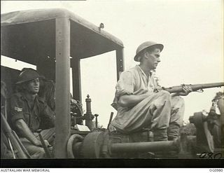 AITAPE, NORTH EAST NEW GUINEA. C. 1944-04. READY FOR JAPANESE SNIPERS, LEADING AIRCRAFTMAN V. N. CHERRY OF OAKEY, QLD, RIDES AS GUARD ON A GRADER DRIVEN BY CORPORAL L. WYMAN OF ROZELLE, NSW, AS NO. ..