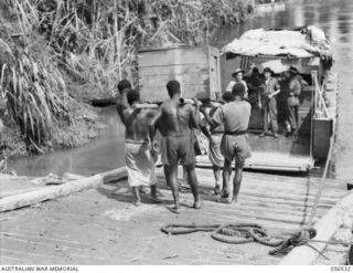 BULLDOG AREA, NEW GUINEA, 1943-09-05. NATIVES LOADING BARGES AT BULLDOG LANDING