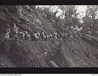 BULLDOG ROAD, NEW GUINEA, 1943-07-17. NATIVES CLEARING BOULDERS AND DEBRIS FROM NEW ROAD ABOUT THREE MILES ABOVE BANNON'S LOOKOUT