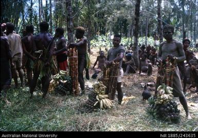 Men standing with fruit piles