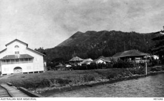 RABAUL, NEW BRITAIN. C. 1916. THE NEW GUINEA COMPANY STORE WITH PART OF THE WHARF IN THE LEFT FOREGROUND. THE HIGHEST BARE PEAK IN THE BACKGROUND IS A USUALLY DORMANT VOLCANO KNOWN LOCALLY AS THE ..