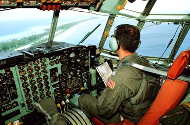 CPT Wayne Shatz, pilot with 374th Tactical Airlift Wing, looks out over an island from the cockpit of his C-130 Hercules aircraft as he flies a Christmas Drop mission. The annual airdrop is a humanitarian effort providing aid to needy islanders throughout Micronesia during the holiday season