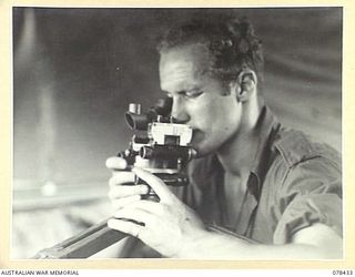 MOTUPINA POINT AREA, BOUGAINVILLE ISLAND. 1945-01-19. VX140745 GUNNER T.M. BASSETT, 2ND FIELD REGIMENT, DOING HIS TURN OF NIGHT FLASH SPOTTING ON THE BEACH NEAR THE UNIT COMMAND POST