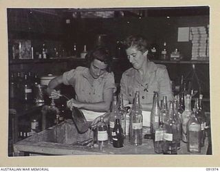 BOUGAINVILLE, 1945-04-19. PRIVATE E.J. HUDSON (1), AND PRIVATE J.X. WASLEY (2), MEMBERS OF AUSTRALIAN ARMY MEDICAL WOMEN'S SERVICE CLEANING MEDICINE BOTTLES AT 2/1 GENERAL HOSPITAL