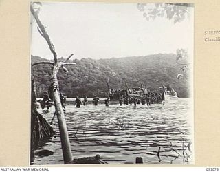 WATU POINT, OPEN BAY, NEW BRITAIN, 1945-05. TROOPS OF B COMPANY, 37/52 INFANTRY BATTALION, WADING ASHORE FROM BARGES, AS THEY ARRIVE AT THEIR NEW CAMP SITE TO RELIEVE 36 INFANTRY BATTALION. THE MEN ..