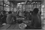 House-building: men share meal of yams in building under construction