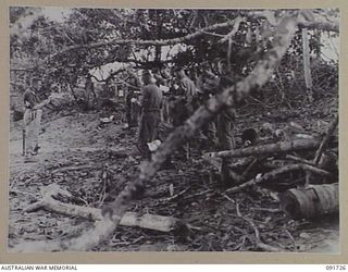 HAWAIN, WEWAK AREA, NEW GUINEA. 1945-05-09. CHAPLAIN L.T. LAMBERT, CHURCH OF ENGLAND, CONDUCTING A THANKSGIVING SERVICE WITH MEMBERS OF 2/3 FIELD REGIMENT, FOR THE CESSATION OF HOSTILITIES IN ..