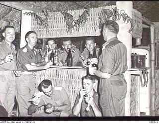 RABAUL, NEW BRITAIN, 1945-12-25. OFFICERS OF 2/4TH ARMOURED REGIMENT DRINKING AT THE BAR AFTER THEIR CHRISTMAS DINNER