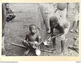 SIPILANGAN, NEW BRITAIN, 1945-07-29. A NATIVE BOY, BEING TRAINED TO ASSIST AT THE REGIMENTAL AID POST, AUSTRALIAN NEW GUINEA ADMINISTRATIVE UNIT DISTRICT SERVICES TOL REFUGEE CAMP, PREPARING A ..