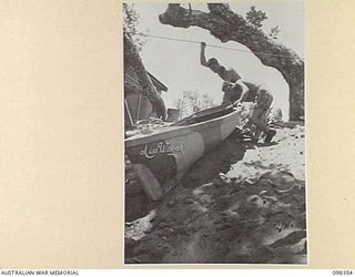 WEWAK, NEW GUINEA. 1945-10-28. PRIVATE K.A. CROCKETT (1) AND PRIVATE L.R. DAVIES (2), MEMBERS OF 16 INFANTRY BRIGADE, EXAMINING THE CONSTRUCTIONAL STAGES OF THEIR ENTRY IN THE WEWAK REGATTA TO BE ..