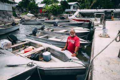 Man standing by aluminium boats, Fakaofo, Tokelau