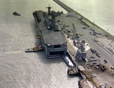 A stern view of the amphibious assault USS SAIPAN (LHA-2) being maneuvered into docking position by tugs