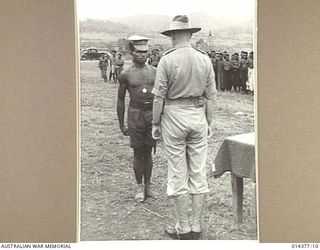 1943-03-03. THE G.O.C. NEW GUINEA FORCE ADDRESSING ONE OF THE NATIVE CONSTABLES AFTER HAVING LR PRESENTED HIM WITH A LARGE SILVER MEDAL FOR LOYAL SERVICE, AND THANKING HIM FOR HIS WORK. ON ONE SIDE ..