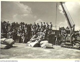 PERSONNEL OF THE 30TH SERVICING UNIT, HEADQUARTERS, ROYAL NEW ZEALAND AIR FORCE, WITH CASES OF AIRCRAFT SPARE PARTS WHICH THEY HAVE JUST UNLOADED FROM A LANDING BARGE. FOR IDENTIFICATION OF 24 ..