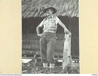 MALAMAL, NEW GUINEA. 1944-07-13. N393309 LIEUTENANT V.C. DIXON, OFFICER COMMANDING, AUSTRALIAN NEW GUINEA ADMINISTRATIVE UNIT NATIVE LABOUR COMPOUND OUTSIDE THE UNIT ORDERLY ROOM