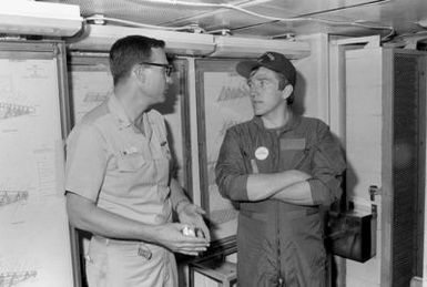 Secretary of the Navy John F. Lehman Jr., right, talks with CDR Nicholas Stasko during Lehman's visit aboard the aircraft carrier USS KITTY HAWK (CV-63)