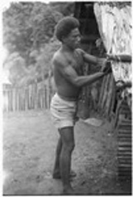 Man hanging shell money on the corner of a house