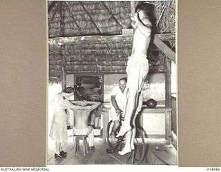 1943-04-01. NEW GUINEA. PHYSIOTHERAPY DEPARTMENT. AT AN AUSTRALIAN GENERAL HOSPITAL IN NEW GUINEA WHICH HAS TAKEN OVER A SPECIALLY CONSTRUCTED NATIVE HUT TO CARRY OUT REHABILITATION TREATMENT - THE ..