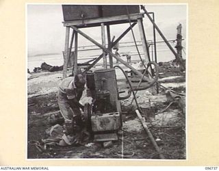 MOEM, WEWAK AREA, NEW GUINEA, 1945-09-17. CRAFTSMAN C.C. BROWN, 2/4 ARMOURED REGIMENT DETACHMENT WITH 4 INFANTRY TROOPS WORKSHOP, WHO IS IN CHARGE OF THE WATER PUMP FOR THE MEN'S SHOWERS. SHOWERS ..