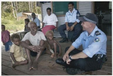 Policeman Mark Hughes, a member of the Australian led Regional Assistance Mission Solomon Islands, chats with villagers at the Isuna outpost in the Weathercoast Region of Guadalcanal, Solomon Islands,  9 November 2004 / David Dare Parker