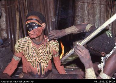 Preparing a dancer for his performance of a curing dance for a sick member of the community