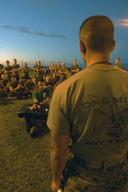 US Marine Corps (USMC) STAFF Sergeant (SSGT) Ramirez (center), Headquarters and Service Battalion (H&S BN), Marine Forces Pacific (MARFORPAC), Camp H. M. Smith, Hawaii (HI), demonstrates how to correctly perform a Ground Elbow exercise, while participating in a unit wide conditioning exercise to enhance their combat readiness and improve their personal physical fitness