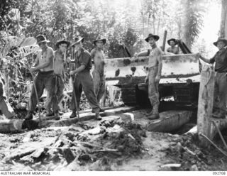 WEWAK AREA, NEW GUINEA. 1945-05-30. MEMBERS OF 2/2 FIELD COMPANY ROYAL AUSTRALIAN ENGINEERS AND 2/8 INFANTRY BATTALION USING A BULLDOZER TO CLEAR DEBRIS AND MUD DURING PREPARATIONS TO BRIDGE A ..