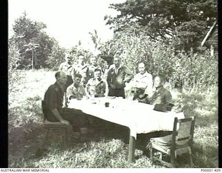 NEW IRELAND, 1945-10. ALLIED AND JAPANESE SERVICE PERSONNEL HOLD A CONFERENCE AT A TABLE IN THE OPEN AIR. (RNZAF OFFICIAL PHOTOGRAPH.)