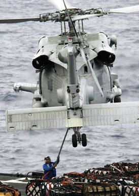 US Navy (USN) flight deck personnel attach a cargo pendant to an MH-60S Seahawk helicopter on the flight deck of the Amphibious Assault Ship USS SAIPAN (LHA 2)