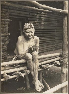 Widows, Ambasi, North Coast [seated woman covered in clay] / Frank Hurley