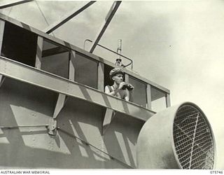 AT SEA. 1944-09/08. SUB-LIEUTENANT R. FREWIN, RAN, ON THE BRIDGE OF THE RAN CORVETTE, GEELONG AS THE VESSEL PROCEEDS ALONG THE COAST OF NEW GUINEA