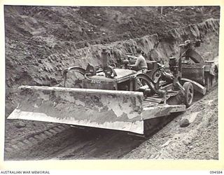 BOUGAINVILLE, 1945-07-31. A BULLDOZER OF 6 MECHANICAL EQUIPMENT COMPANY, ROYAL AUSTRALIAN ENGINEERS, TOWING A CARRYALL LOADED WITH SAND FOR TOP DRESSING THE BUIN ROAD