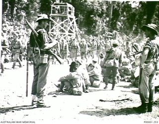 THE SOLOMON ISLANDS, 1945-09-19. JAPANESE SOLDIERS AND AUSTRALIAN GUARDS WATCH AS MORE JAPANESE TROOPS ARRIVE AT AN INTERNMENT CAMP ON BOUGAINVILLE ISLAND. THE JAPANESE HAD BEEN SERVING ON NAURU ..