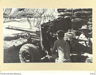 MILILAT, NEW GUINEA. 1944-07-27. VX84730 GUNNER O.E. FLANNERY (1) AND VX84765 GUNNER C.R. MCKILLOP (2) OF THE 22ND BATTERY, 106TH TANK ATTACK REGIMENT LOADING THEIR 6 POUNDER GUN IN THEIR ..