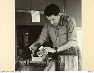 PORT MORESBY, PAPUA, 1944-02-26. TX11281 SIGNALMAN R. TOWNSEND, 18TH LINES OF COMMUNICATION SIGNALS (1) REMOVING A MESSAGE FROM THE ELECTRIC MESSAGE CONVEYOR WHICH OPERATES BETWEEN THE NEW GUINEA ..