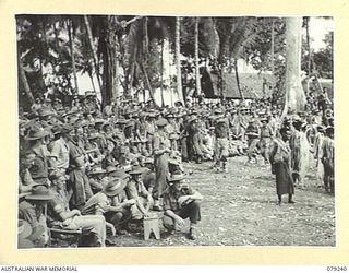 MANGUNUI, JACQUINOT BAY, NEW BRITAIN. 1945-02-25. AUSTRALIAN SERVICE PERSONNEL WATCHING WITH INTEREST THE DANCERS AT A NATIVE SING- SING AT THE AUSTRALIAN NEW GUINEA ADMINISTRATIVE UNIT NATIVE ..