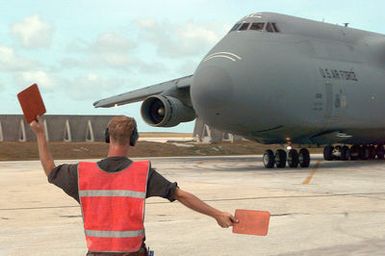 STAFF Sergeant Jim Driesbaugh, Electro-Environmental Systems SPECIALIST, 634th Air Mobility Support Squadron, Andersen Air Force, Guam, marshals in a C-5 Galaxy aircraft out of Travis Air Force Base, California, as it arrives at Andersen Air Force Base with power trucks (not shown) from Hawaii. The trucks will aid the Guam Power Authority in restoring power to the island after Typhoon Paka