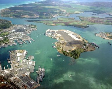 An aerial view of Pearl Harbor with the nuclear-powered aircraft carrier USS ENTERPRISE (CVN-65) visible to the left, bottom, and the nuclear-powered aircraft carrier USS CARL VINSON (CVN-70) visible to the right