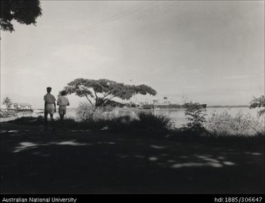 Two people walking along the water