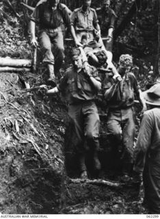 SHAGGY RIDGE, NEW GUINEA. 27th December, 1943. A stretcher party of the 2/16th Australian Infantry Battalion, 21st Australian Infantry Brigade negotiating a difficult section of the track with a ..